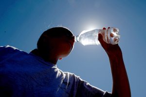 person drinking water backlit by sun