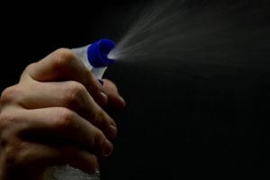 hand spraying a bottle of a cleaning/disinfectant solution in a home