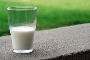 glass of milk sitting outside with grass in background