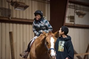 A happy boy riding a horse that another boy is leading
