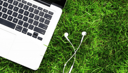 computer keyboard and earbuds in the grass