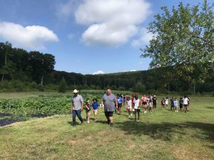 Mashantucket youth and leaders walk along the vegetable garden at the farm
