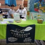 3 women behind a green master gardener program table