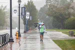 students walking in the rain on the UConn campus