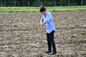woman with a soil probe in the middle of an agricultural field