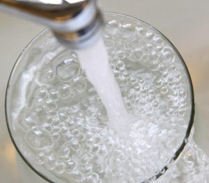 faucet running into a cup with bubbles and water running over the lip of the cup