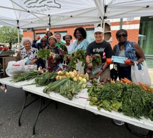 group of people at farmers' market table with vegetables in front of them