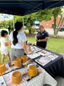 Jacqueline Kowalski talking to a woman and child about urban agriculture under a tent at the farmers market