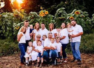 three generations of the Logue family standing together in front of the corn at sunset