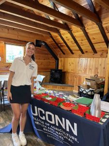 Olivia Routhier in front of a table of UConn items