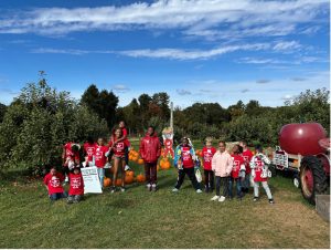 MPTN apple picking group in front of the trees with a large apple statue on right