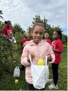 girl in pink sweater with bag of apples