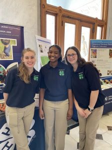 three teen girls wearing blue polo shirts with 4-H emblem and smiling