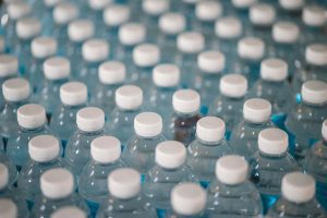 Many plastic water bottles with blue labels and white caps lines up in diagnonal rows.