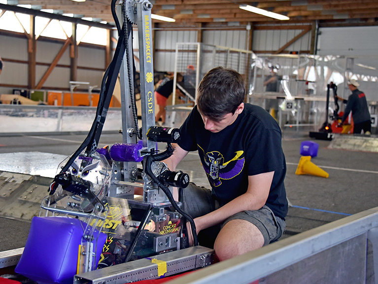 4-H student looking at a robotics machine