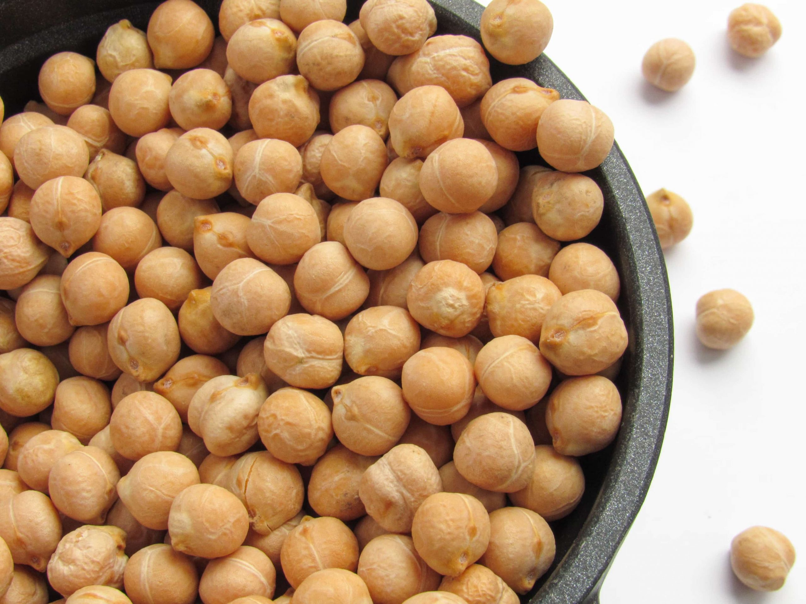 (Karyna Panchenko/Unsplash) A black stone bowl filled with tan, round chickpeas against a white background.