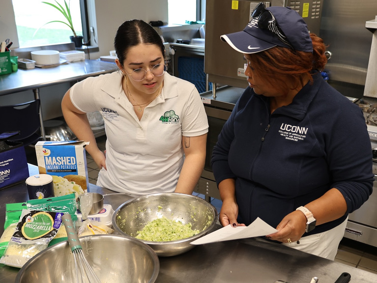 two people standing in a kitchen looking at a recipe