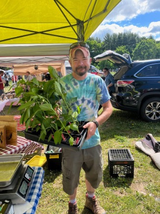 Mitchel Colgan holding a flat of vegetables at a farmers' market