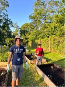 Dinyar standing in front of a raised bed at Fodor Farm with a boy in the background